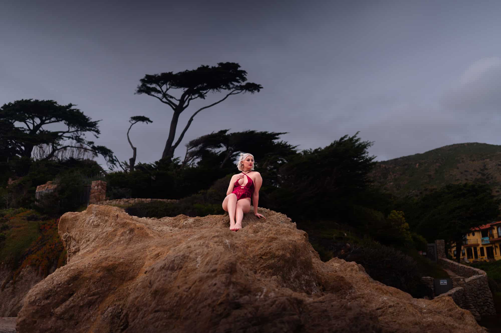 Sitting Beach Boudoir photography in a red bodysuit on top of Rocks at El Matador in Los Angeles by Eli Boudoir