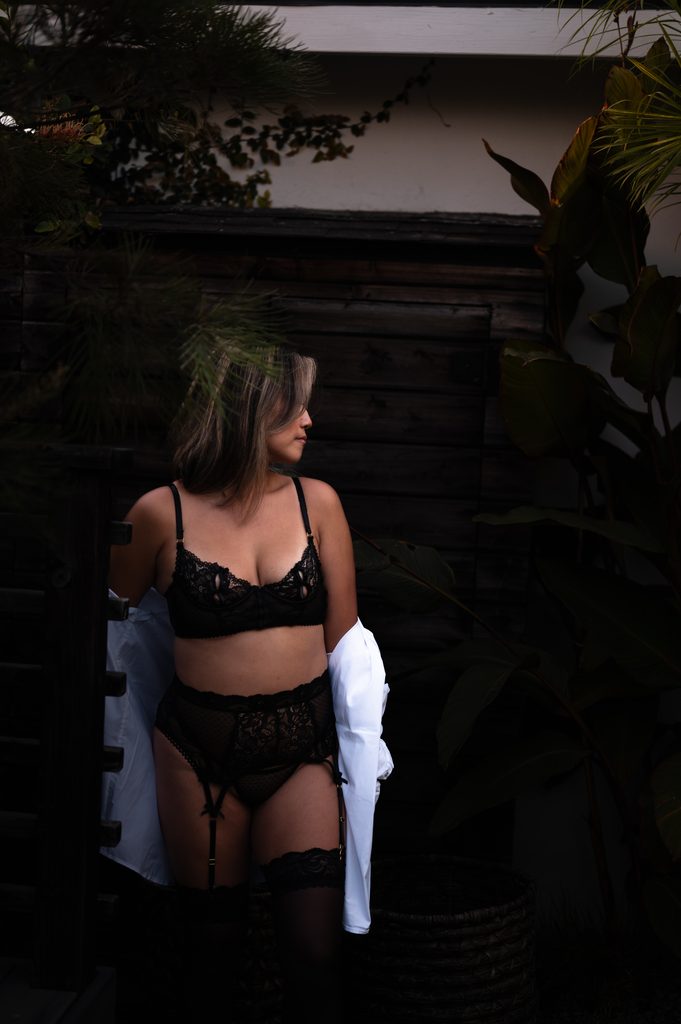 boudoir photography of a client wearing a three piece lingerie set with a garter belt and thigh high stockings.
