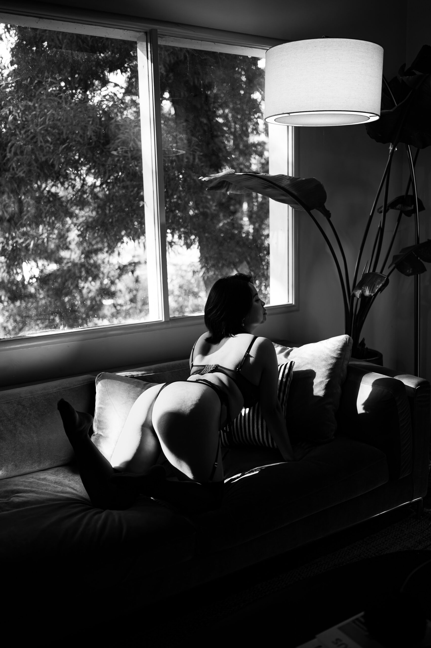 luxury boudoir photography in Los Angeles CA.. This model is kneeling on the couch with her legs bent behind herself.