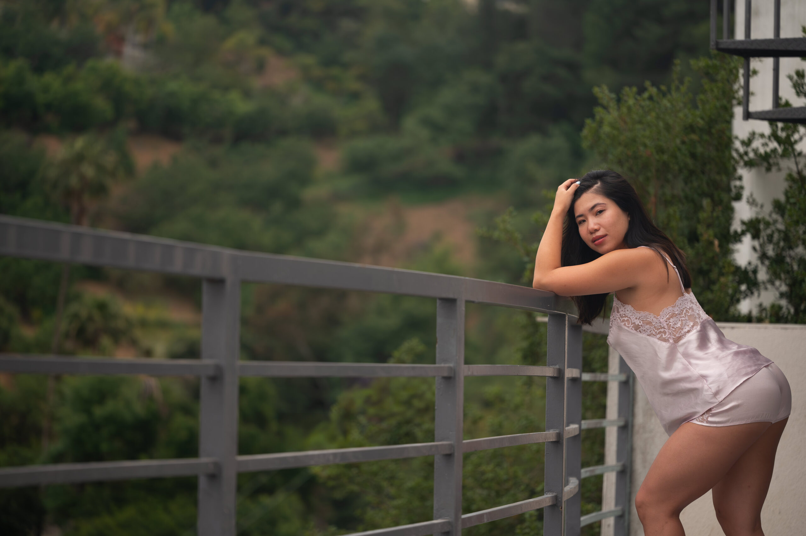 A complete guide to boudoir posing what happens during your boudoir session. This photograph was taken by ELI Boudoir. it is of a woman posing over a guard rail wearing a stunning slip dress.