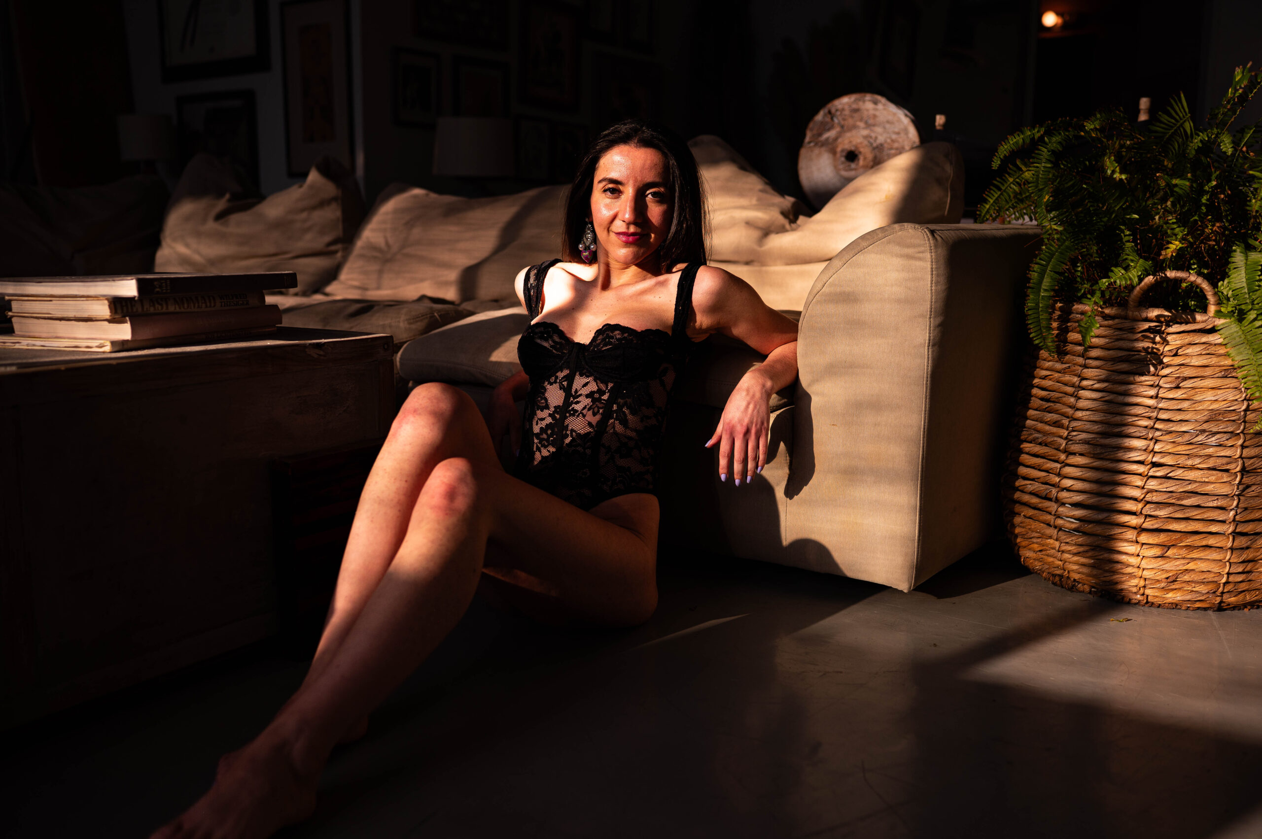Los Angeles boudoir photography, where to buy boudoir lingerie in los angeles. This photograph is striking and of a woman leaning against a couch wearing a black bodysuit.